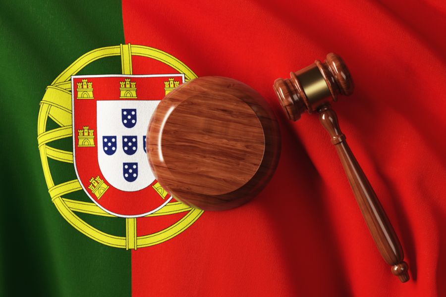 Foto de um malhete sobre uma bandeira de Portugal, ilustrando a lei 93/2021 portuguesa.