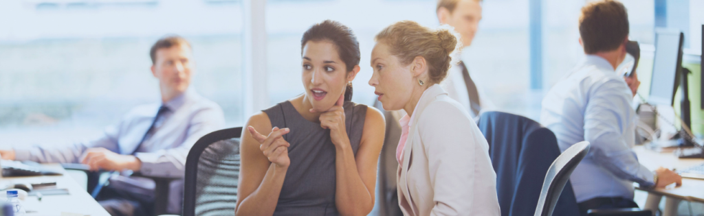 Colaboradoras em ambiente corporativo a conversar de forma reservada, ilustrando a importância da confidencialidade no canal de denúncias.