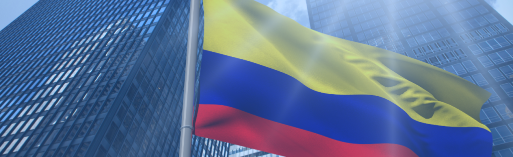 Bandera de Colombia ondeando frente a edificios corporativos modernos, representando cumplimiento y transparencia empresarial en el país.